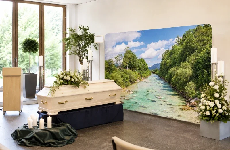 Moderne Trauerhalle mit hellem Sarg und großer Zipper-Wall mit Fluss-Isar-Motiv als stilvolle Dekoration für eine würdevolle Trauerfeier.
