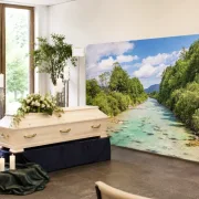 Moderne Trauerhalle mit hellem Sarg und großer Zipper-Wall mit Fluss-Isar-Motiv als stilvolle Dekoration für eine würdevolle Trauerfeier.