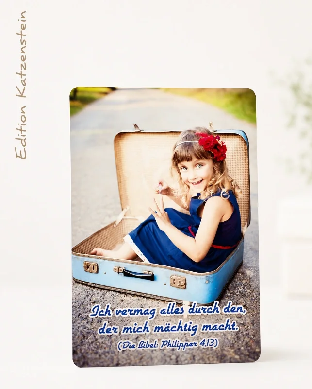 Christliche DIN-A6-Postkarte mit lächelndem Mädchen im Koffer und dem Bibelvers „Ich vermag alles durch den, der mich mächtig macht.“ (Philipper 4,13).