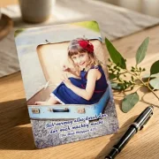 Christliche Postkarte auf Schreibtisch mit Motiv eines Mädchens, das in einem Reisekoffer sitzt