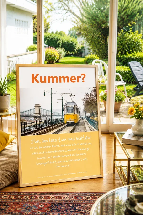 Hochwertiges Produktfoto des christlichen Posters „Kummer? – Ihn, ihn lass tun und walten!“ von Edition Katzenstein im Format DIN A2 in einem hellen Wohnzimmer mit Blick in einen gepflegten Garten.