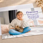 DIN-A4-Poster zur Jahreslosung 2027 mit Mädchen und Katze auf einem hellen Leinentisch