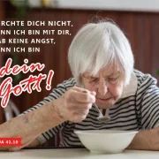 Ältere Frau allein am Tisch auf einer Postkarte zur Jahreslosung 2027 aus Jesaja 41,10