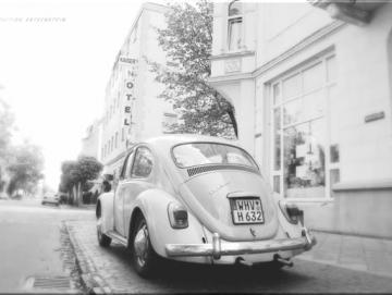 Leinwanddruck: Weißer VW Käfer auf Bürgersteig