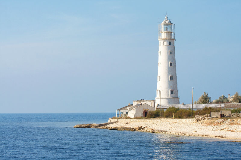 Leinwanddruck Weißer Leuchtturm mit Nebengebäuden