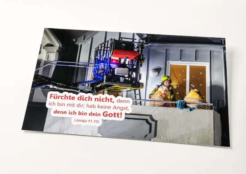 Jahreslosung 2027 als hochwertiges DIN-A2-Poster - Edition Katzenstein Freigestelltes DIN-A2-Poster zur Jahreslosung 2027 mit Feuerwehrmann und älterem Ehepaar