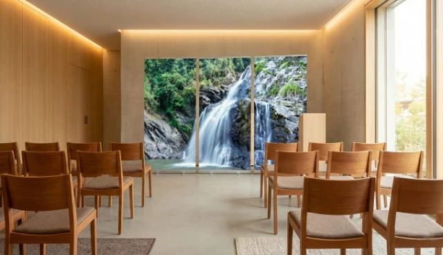 Drei Roll-Up-Displays mit einem Wasserfall-Motiv stehen nebeneinander in einer modernen Trauerhalle mit Holzstühlen und heller Wandgestaltung.