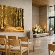 Wandbanner mit Baumallee in warmer Nachmittagssonne über einem Sarg in moderner Trauerhalle mit Blumenschmuck