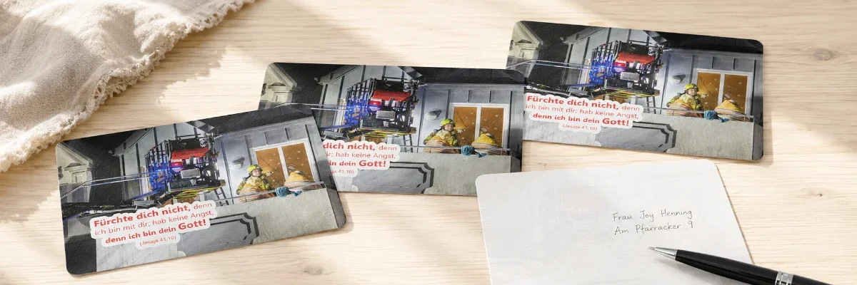 Postkarten zur Jahreslosung 2027 auf einem Holztisch liegnend
